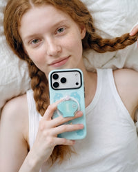Holding the dolphin cove phone case close with the seashell pop-grip lifted off the back for an easy grip