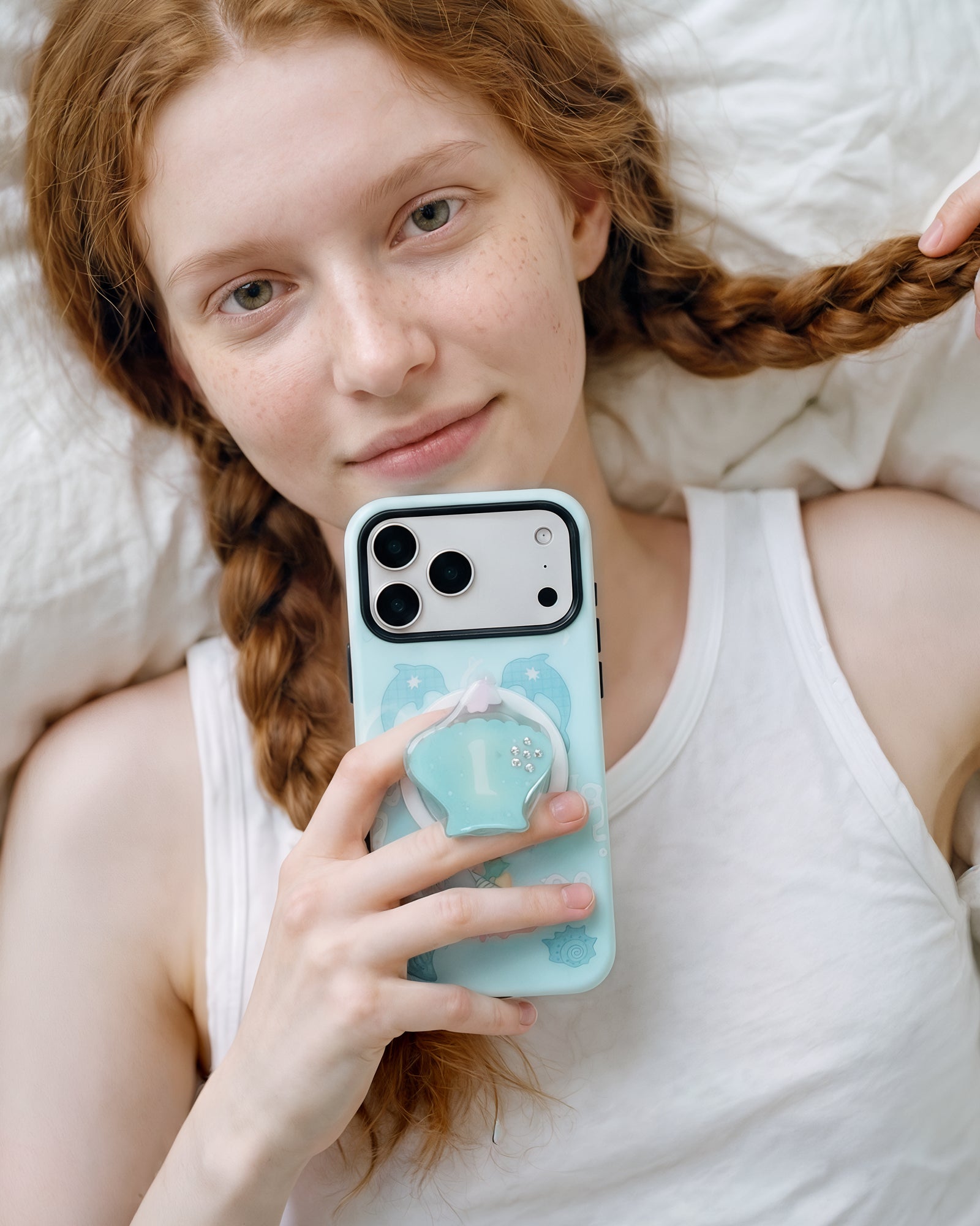 Holding the dolphin cove phone case close with the seashell pop-grip lifted off the back for an easy grip
