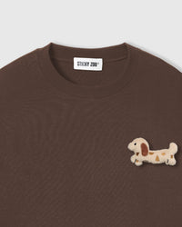 Close-up of spotted dachshund plush on brown cotton showing tonal cream and brown detail