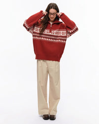 Model wearing STICKYZOO Holiday Sweater in red showing full body relaxed proportions and quarter-zip collar