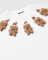 Detail of individual gingerbread plush character on white STICKYZOO sweatshirt with icing outlines