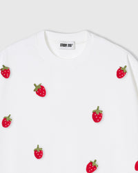 Close-up of plush strawberry applique showing red body, white seed dots, and green felt stem
