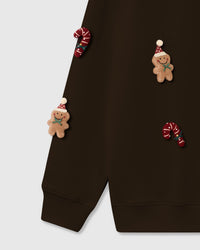 Lower section detail of STICKYZOO Gingerbread Party Crashers Sweatshirt showing plush appliques on sleeve and body with ribbed cuffs