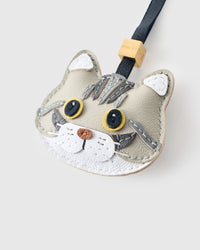 Tight close-up of the Silver Tabby American Shorthair face — gold eyes in real leather, hand-stitched silver tabby markings, copper heart-shaped nose. Every panel by hand.
