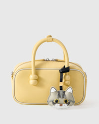 Silver Tabby American Shorthair styled on a soft-yellow box bag, front — a small, specific piece that turns a simple bag into a personal one.