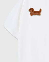 Detail of hand-stitched plush dachshund on white Dash Dachshund T-Shirt sleeve showing 3D texture