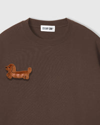 Close-up of plush dachshund applique on brown cotton showing tonal texture and 3D dimension