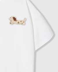 Close-up of spotted dachshund plush on shoulder area of white tee showing plush detail