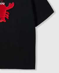 Side angle of plush shrimp character on black cotton showing three-dimensional depth