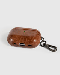 Back view of cognac croc case showing USB-C port, speaker cutouts, and metal carabiner