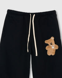 Detail of hand-stitched teddy bear applique on STICKYZOO black sweatpant showing dimensional craft