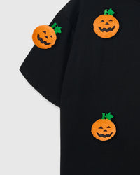 Multiple plush pumpkins on STICKYZOO black tee showing dimensional scatter pattern