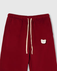 Close-up of check-ear plush teddy bear face on red cotton sweatpant showing gingham ear detail