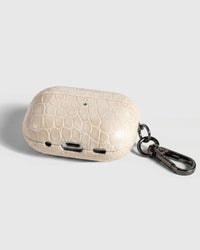 Back view of ivory croc case showing USB-C port, speaker cutouts, and metal carabiner
