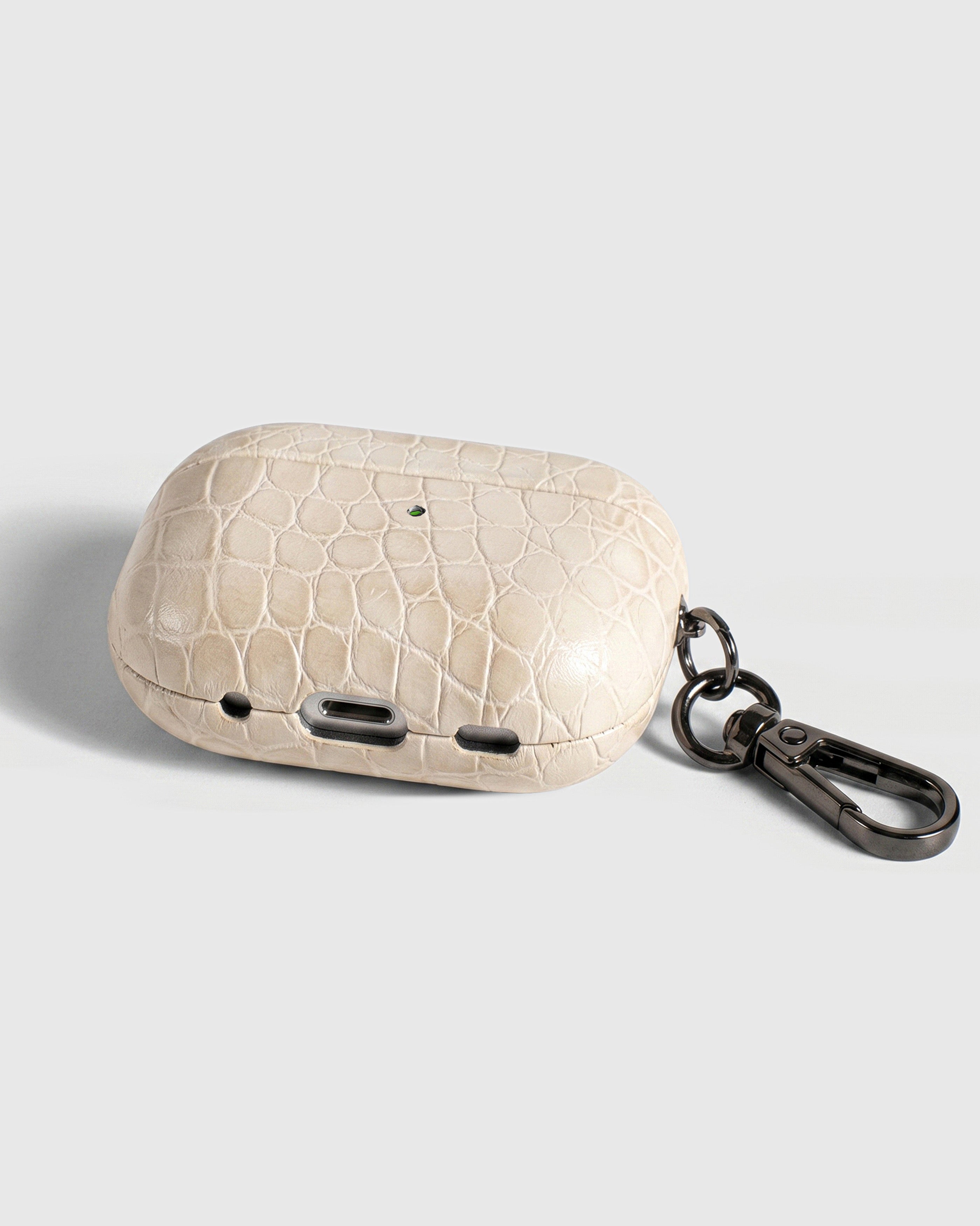 Back view of ivory croc case showing USB-C port, speaker cutouts, and metal carabiner