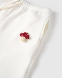 Close-up of hand-stitched plush fly agaric mushroom applique showing red polka dot cap and cream stem on premium cotton