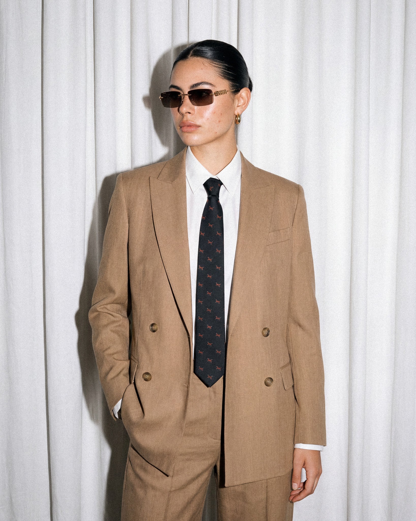 Pieces people recognize Model in tan double-breasted suit wearing STICKYZOO Dachshund Tie, relaxed pose showing full tie drape