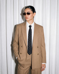 Pieces people recognize Model in tan double-breasted suit wearing STICKYZOO Dachshund Tie, relaxed pose showing full tie drape