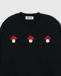 Close-up of 3D plush mushroom applique showing red polka-dot cap and cream stem on black cotton