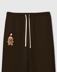 Close-up of plush gingerbread man applique on dark brown STICKYZOO sweatpant showing Santa hat and icing detail