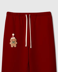 Close-up of plush gingerbread man applique with Santa hat and green bow on red heavyweight cotton fleece