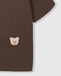 Close-up of single plush bear face near hem of Khaki Teddy Check-Ear T-Shirt