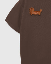 Detail of plush dachshund on brown Dash Dachshund T-Shirt sleeve showing dropped shoulder silhouette