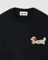 Close-up of spotted dachshund plush on black 230gsm cotton showing cream body and brown markings