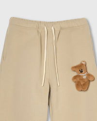 Detail of hand-stitched teddy bear applique on STICKYZOO cream sweatpant showing dimensional craft
