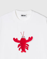 Close-up of plush shrimp on white cotton showing red body, googly eyes, and antennae