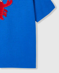 Side angle of plush shrimp character showing dimensional depth on royal blue cotton