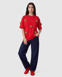 Model styling red Poodle Parade T-Shirt with hands in pockets showing relaxed silhouette