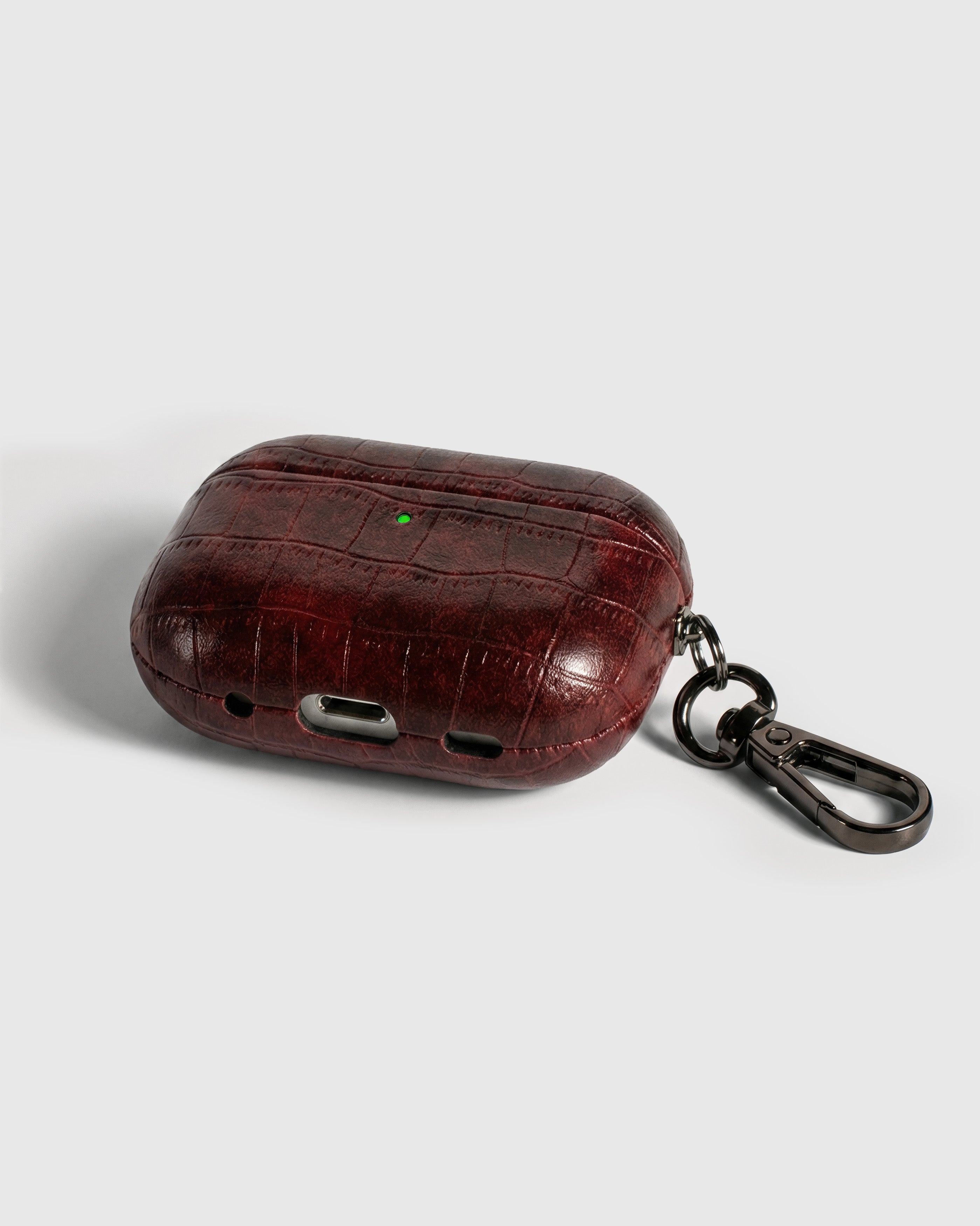 Back view of antique burgundy vintage croc case showing USB-C port, speaker cutouts, and metal carabiner