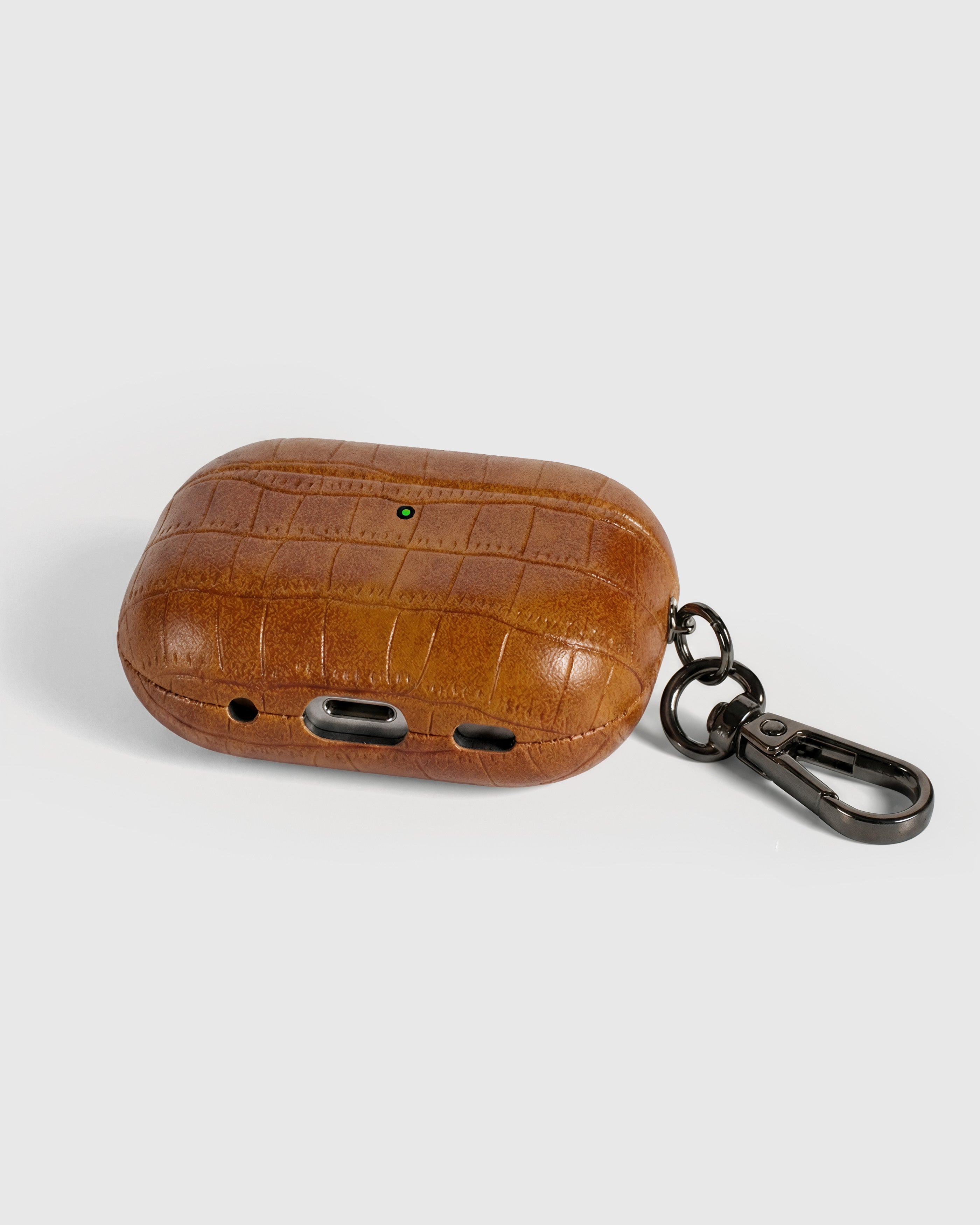 Back view of cognac vintage croc case showing USB-C port, speaker cutouts, and metal carabiner