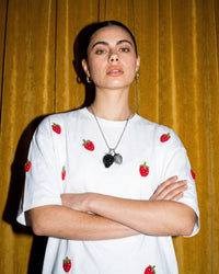 Model wearing STICKYZOO Strawberry T-Shirt in white showing dropped shoulders and scattered plush strawberries