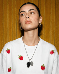 On-model close-up of STICKYZOO Strawberry T-Shirt in white with beaded strawberry necklace