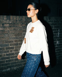 Side profile of model wearing white Saint Teddy Bear Sweatshirt showing plush bears