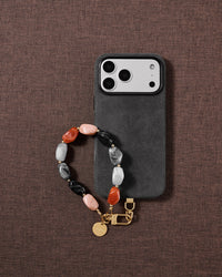 Lifestyle flat-lay of the multi-tone agate wrist strap on soft fabric, each piece assembled by hand bead by bead rather than factory made.