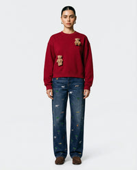 Model wearing STICKYZOO Saint Teddy Bear Sweatshirt in red showing cropped boxy silhouette and plush bear detail