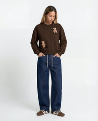 Model wearing dark brown Saint Teddy Bear Sweatshirt showing dropped shoulders and streetwear proportions