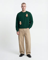 Model wearing STICKYZOO Saint Teddy Bear Sweatshirt in forest green showing boxy silhouette and plush detail