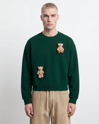 Lifestyle shot of forest green Saint Teddy Bear Sweatshirt showing full styling and dropped shoulders