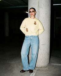 Lifestyle shot of Saint Teddy Bear Sweatshirt in lemon with casual pairing