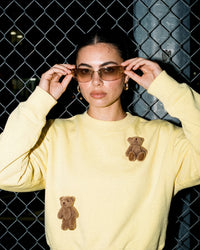 Model wearing lemon Saint Teddy Bear Sweatshirt showing plush bear detail up close